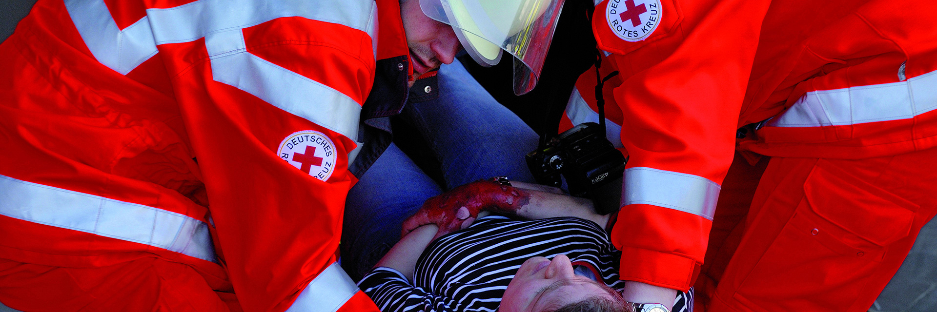 buehnenbild_leitbild.jpg Foto: Zwei Helfer der DRK-Bereitschaften tragen eine verletzte Fau.